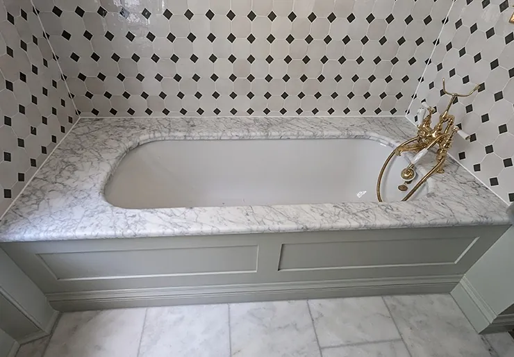 Marble bath surround with a fresh sealant joint along the tiled walls